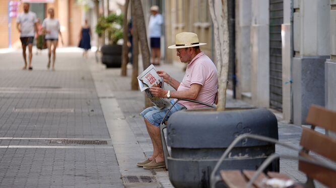 Un hombre lee el periódico en el centro de Huelva