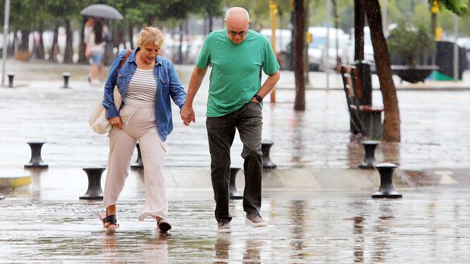 Una pareja anda bajo la lluvia en Huelva.