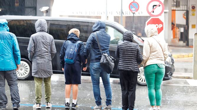 Ciudadanos con chubasqueros bajo la lluvia.