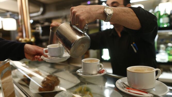 Un camarero sirve un café con leche en un establecimiento