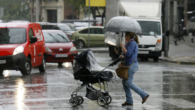 Una mujer se protege de la lluvia con su paraguas en el centro de Huelva