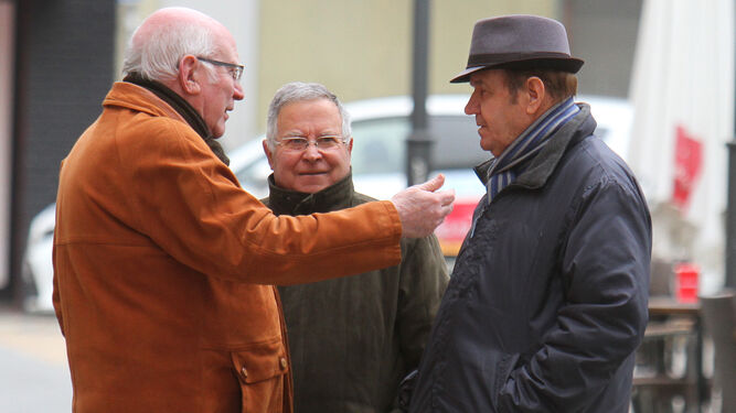 Tres hombres conversan en la calle con temperaturas frías