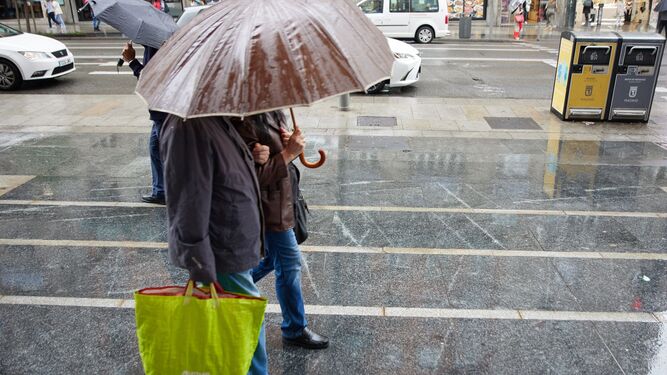 Una pareja se protege de la lluvia con un paraguas.