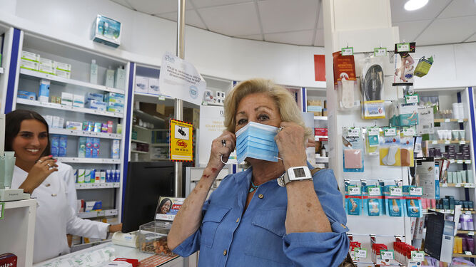 Una clienta se pone la mascarilla en una farmacia.