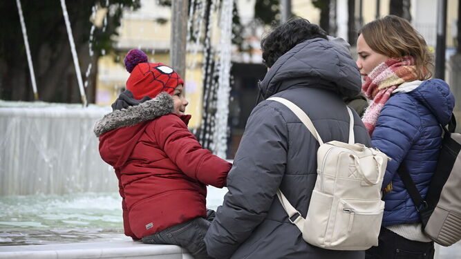 Tres onubenses se protegen del frío en las calles de Huelva este lunes