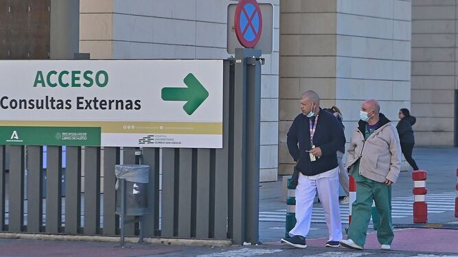 Personas con mascarilla junto a un centro hospitalario en Granada.