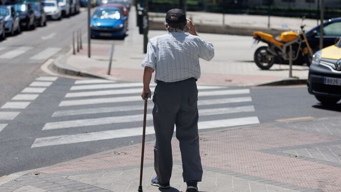 Un hombre de avanzada edad avanza hacia un paso de peatones