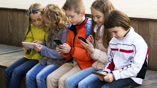 Niños con teléfonos móviles en un colegio.
