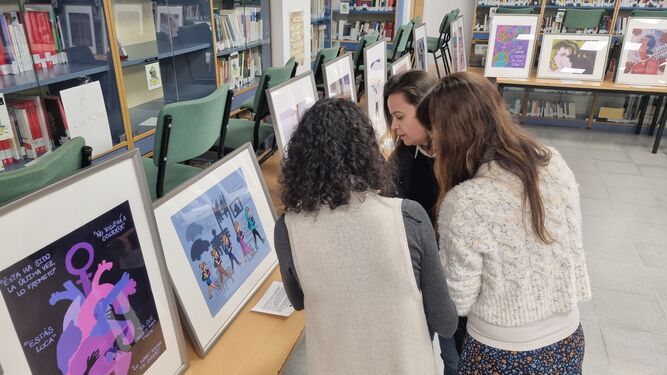 Tres mujeres observan una de las muestras de la exposición itinerante sobre violencia machista en los institutos de Aljaraque.