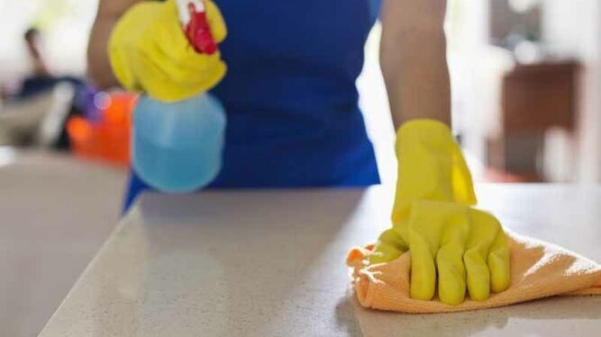 Una mujer limpia la encimera de una cocina.