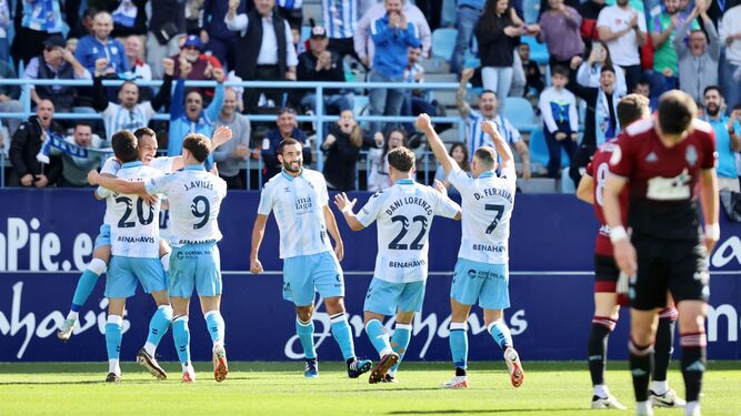 Jugadores del Málaga celebran uno de sus goles ante recreativistas cabizbajos.