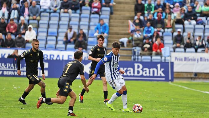 Los jugadores de la AD Ceuta presionan a Miguelete que protege el balón.
