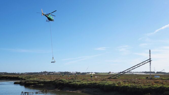 El helicóptero de Endesa transporta un bloque de hormigón sobre las marismas del Piedras