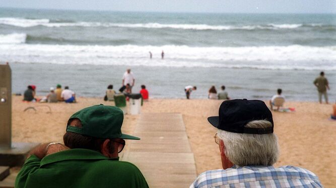 En la playa de La Antilla dos hombres observan el estado del mar.