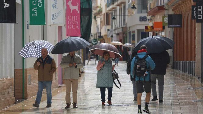 Onubenses con sus paraguas este sábado en el centro de Huelva