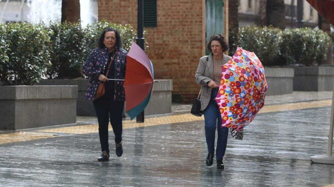 Dos señoras con sus paraguas este domingo en Huelva