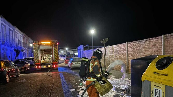 Uno de los bomberos sofoca el incendio en los contenedores de Rociana