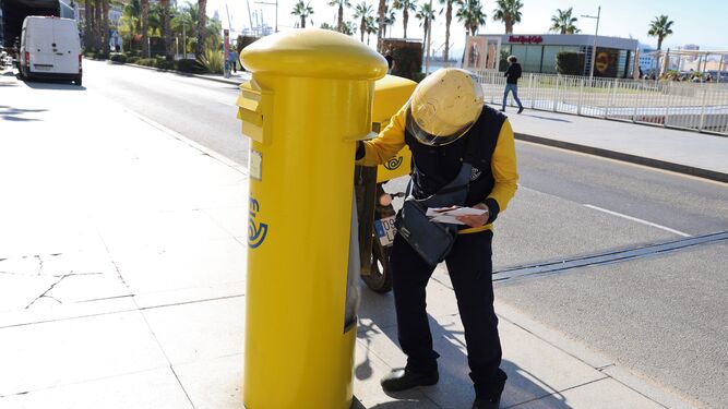Un empleado de Correos revisando un buzón junto al puerto de Málaga.